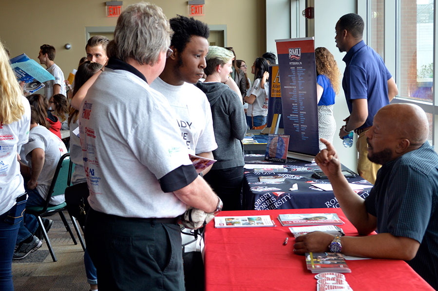 Young man talking with a seated recruiter at a college fair